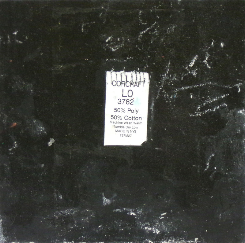 A black color field with a tag from a uniform pasted in the center. The tag indicates the garment is 50-50 cotton-polyester and also shows washing instructions.